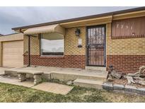 Charming brick home with a secure front entrance featuring a decorative security door, awning, and a small front garden at 7251 Larsh Dr, Denver, CO 80221