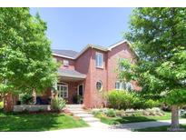 Inviting two-story brick home featuring a well-manicured lawn and mature trees at 7527 E Severn Pl, Denver, CO 80230