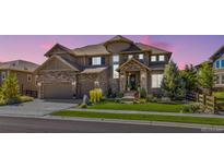 Stunning two-story home showcasing a manicured front lawn, a stone and siding exterior, and a three-car garage at 22198 Boundstone Dr, Parker, CO 80138