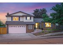 Charming two-story home with brick and siding exterior, landscaping, and inviting front entrance at sunset at 15034 E Floyd Ave, Aurora, CO 80014