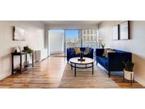 Inviting living room featuring hardwood floors, two blue sofas, modern artwork and sliding glass doors to a balcony at 888 N Logan St # 5A, Denver, CO 80203