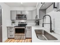 Modern kitchen features gray cabinetry, stainless steel appliances, and white subway tile backsplash at 888 N Logan St # 5A, Denver, CO 80203