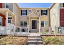 Charming two-story home with a welcoming entrance and a white picket fence surrounding the front yard at 1496 Red Cliff Way, Castle Rock, CO 80109