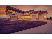 Expansive home featuring a three-car garage, stone accents, and a cozy porch, all under a vibrant sunset sky at 1012 S Addison Way, Aurora, CO 80018