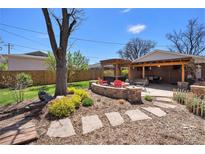 Beautiful backyard with a stone patio, firepit, pergola, and mature landscaping at 2064 Ironton St, Aurora, CO 80010