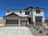 Two-story home featuring a three-car garage, stone accents, and a modern color palette at 1733 Fox Trotter Pt, Castle Rock, CO 80104