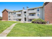 Multi-story apartment building featuring balconies, green lawn and brick accents at 10150 E Virginia Ave # 7-302, Denver, CO 80247