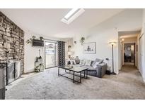 Bright living room features a stone fireplace, plush carpet, and sliding glass doors to a patio at 10150 E Virginia Ave # 7-302, Denver, CO 80247