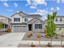 Beautiful two-story home featuring stone accents, gray siding, a two-car garage, and manicured landscaping at 25323 E Warren Pl, Aurora, CO 80018