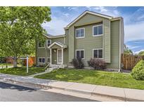 Inviting two-story home with green siding, a well-manicured lawn, and mature trees for shade at 5713 Whitechapel St, Castle Rock, CO 80104