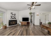 Inviting living room featuring a fireplace, modern ceiling fan, and wood-look laminate flooring at 5532 Umatilla St, Denver, CO 80221