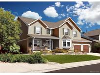 Two-story house with landscaped yard, attached garage, and inviting front porch at 2834 S Fig St, Lakewood, CO 80228