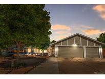 Charming single-Gathering home boasts a three-car garage and a well-maintained front yard at dusk at 16673 E Kent Dr, Aurora, CO 80013