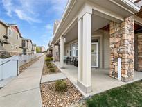 Inviting front porch with stone accents, covered seating, and meticulously landscaped surroundings at 10818 Cimarron St # 307, Firestone, CO 80504