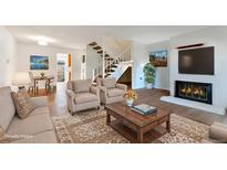 Bright living room featuring a fireplace, staircase, and comfortable seating at 1235 S Monaco Pkwy, Denver, CO 80224