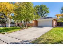 Charming brick home featuring a well-manicured front yard, a long driveway, and an attached two-car garage at 6642 S Pearl St, Centennial, CO 80121