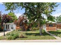 Charming brick home with mature trees, landscaped yard, and covered front porch at 8991 Hickory Pl, Thornton, CO 80229