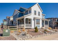 Charming two-story home with white siding and a covered porch, complemented by rocky landscaping at 8409 Rush Creek Ave, Littleton, CO 80125