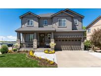 Charming gray two-story home with stone accents, a welcoming front porch and manicured lawn at 110 Ferris Ln, Erie, CO 80516