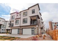 Modern three-story townhome with white siding, stone accents, and two-car garage at 1990 S Holly St # 4, Denver, CO 80222