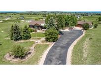 Expansive ranch-style home features a long driveway with well-manicured landscaping and a lush, green lawn at 1505 Legacy Trl, Elizabeth, CO 80107
