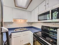 Compact kitchen featuring white cabinets, blue countertops, and modern appliances at 1720 S Ammons St # A, Lakewood, CO 80232