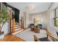Cozy living room featuring hardwood floors, a stylish rug, and natural light from the windows at 187 S Pearl St, Denver, CO 80209
