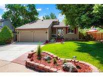 Charming home featuring a well-manicured lawn, lovely landscaping, and a two-car garage, all under a bright blue sky at 7344 S Sheephorn Mtn, Littleton, CO 80127