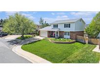 Charming two-story home featuring a well-manicured front yard with an inviting garden and mature trees at 6731 Devinney St, Arvada, CO 80004
