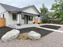 Charming exterior view of the home's front yard featuring mature trees, mulched garden, and well manicured landscaping at 1694 Xanthia St, Denver, CO 80220