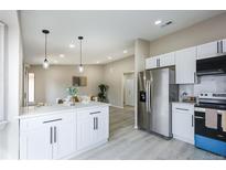 Bright, renovated kitchen with stainless steel appliances and light gray flooring open to the living area at 1075 S Garrison St # 201, Lakewood, CO 80226