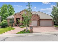 Charming brick home with a well-manicured lawn, beautiful landscaping, and a two-car garage at 2587 S Harlan Ct, Lakewood, CO 80227