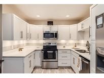 Bright kitchen features white cabinets, stainless steel appliances, and under-cabinet lighting at 3144 S Wheeling Way # 401, Aurora, CO 80014