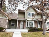 Green two-story townhome with brick facade, front steps, and landscaping at 2131 Ranch Dr, Denver, CO 80234