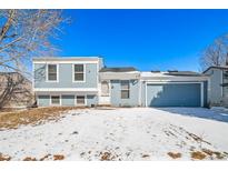 Charming light blue two-story home featuring a front-facing two car garage and snow-covered yard at 20615 E Coolidge Pl, Aurora, CO 80011
