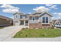 Beautiful two-story home with gray siding, stone accents, well-manicured lawn, and a two-car garage at 19471 W 59Th Ave, Golden, CO 80403
