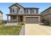 Charming two-story home with stone accents, a covered porch, and a well-manicured lawn at 7360 S Old Hammer Way, Aurora, CO 80016