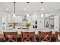 Bright, open kitchen features white cabinets, stainless appliances, granite countertops, and pendant lighting at 9805 Keenan St, Highlands Ranch, CO 80130