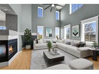 Bright living room with tall windows, fireplace, and large sectional couch at 5906 S Youngfield Way, Littleton, CO 80127