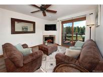 Inviting living room featuring a cozy fireplace, plush seating, and a sliding glass door to a deck at 34 Highfield Trl # 311, Breckenridge, CO 80424