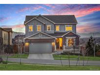 Charming two-story home features a brick and gray exterior with a two-car garage, lush lawn, and mountain views at 12917 Fox St, Westminster, CO 80234
