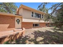 Charming home featuring a two-tone exterior, brick accents, front door wreath, and lush landscaping at 30321 Chestnut Dr, Evergreen, CO 80439