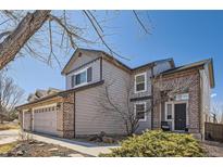Charming two-story home featuring a two car garage, brick accents, and manicured landscaping under a bright blue sky at 10215 Kleinbrook Way, Highlands Ranch, CO 80126