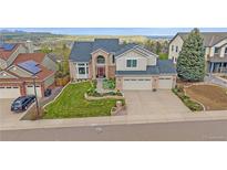 Beautiful two-story home with a well-manicured front yard, three car garage, and green landscaping at 15887 W Ellsworth Ln, Golden, CO 80401