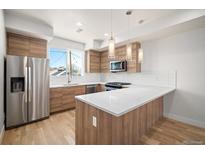 Modern kitchen featuring stainless steel appliances, wooden cabinetry, sleek countertops and stylish pendant lighting at 3520 W Conejos Pl # 11, Denver, CO 80204