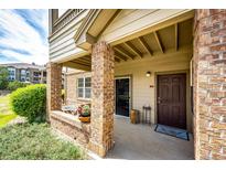 Cozy covered patio with brick columns, seating area, and a view of the surrounding greenery at 12820 Ironstone Way # 103, Parker, CO 80134