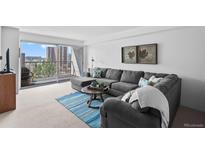 Bright living room with gray sectional, balcony access, and city views at 2 Adams St # 806, Denver, CO 80206