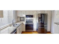 Well-lit kitchen features stainless steel appliances, granite countertops, and white cabinets at 1050 S Monaco Pkwy # 38, Denver, CO 80224