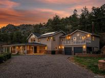 Stunning two-story home with a balcony, complemented by a gravel driveway and mountain views at sunset at 2571 Sw Grapevine Rd, Idledale, CO 80453