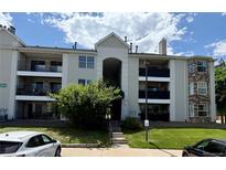 Multi-level condo building with balconies, stone accents, tidy landscaping, and street parking at 12304 W Cross Dr # 304, Littleton, CO 80127